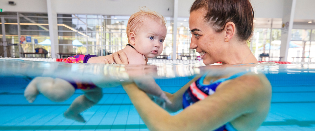 Child swimming underwater with swim teacher or instructor