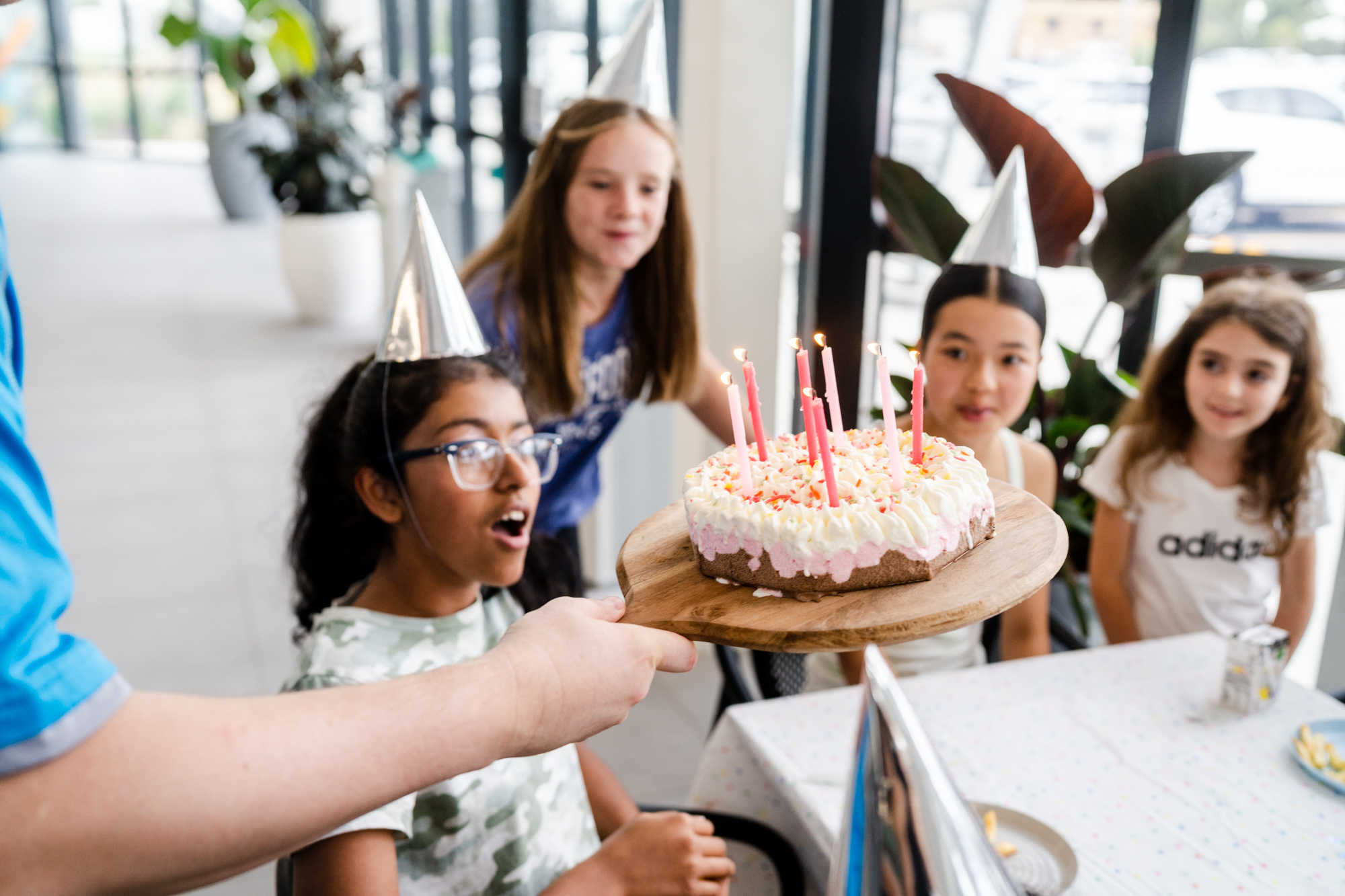 Photo of a group of four girls celebrating a birthday party including a cake with candle.